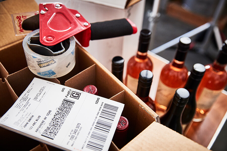 FedEx shipping documents and wine packed in open boxes