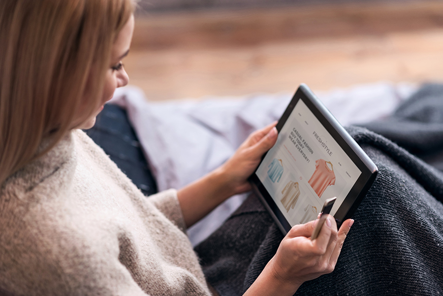 Female with dark hair shops online on iPad with credit card in hand