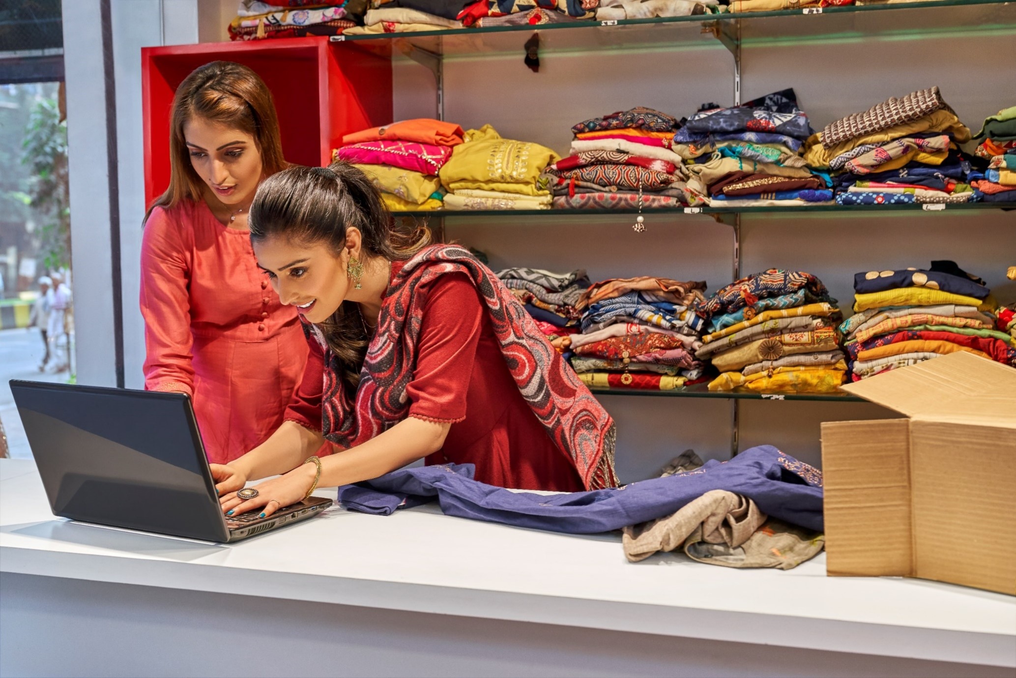 Indian female business owners with laptop inside fabric warehouse