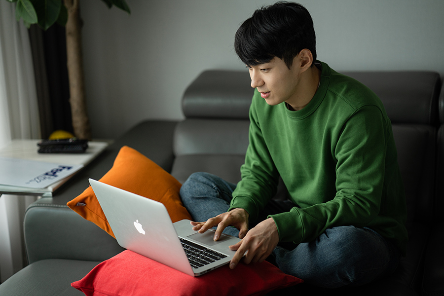 A man sitting on sofa and using laptop