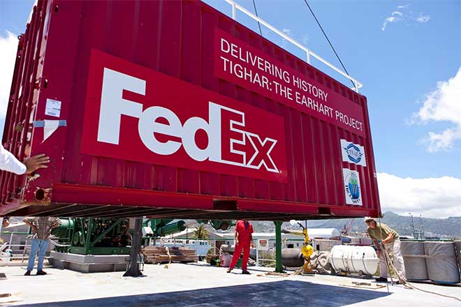 Large red FedEx shipping container lifted by crane