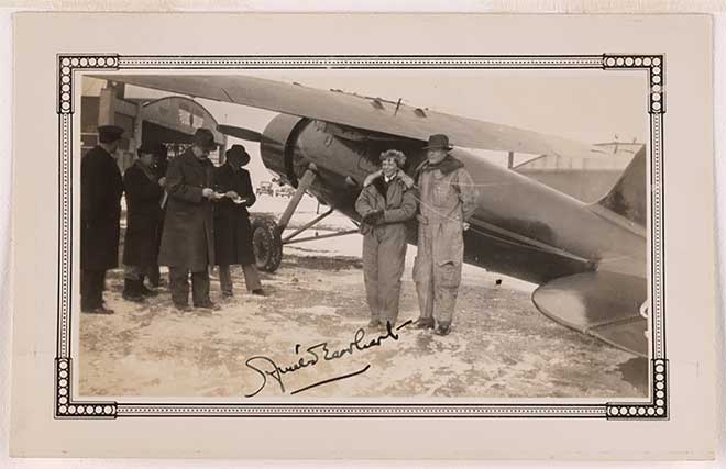 Signed black and white photo of male and female aviator beside old plane