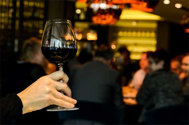 Female hand holds glass of red wine in bar