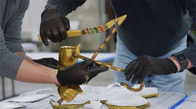 2 people with black gloves restoring gold Egyptian artefacts