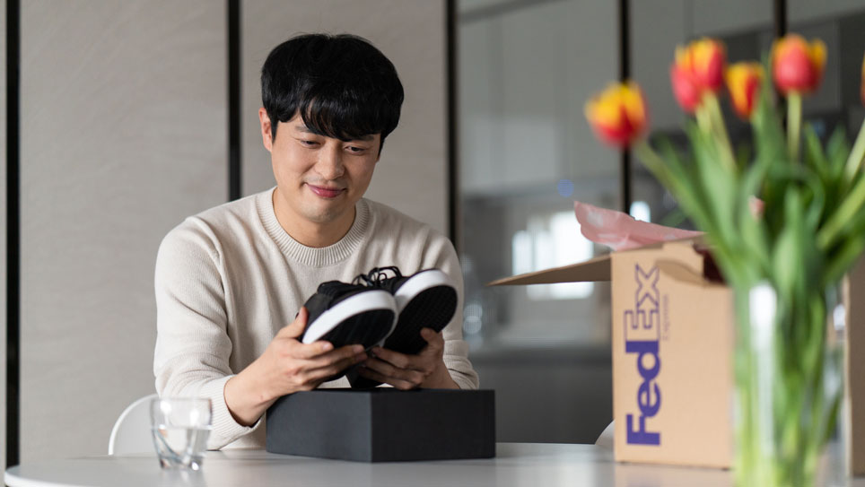 Asian male opens new shoes from FedEx box