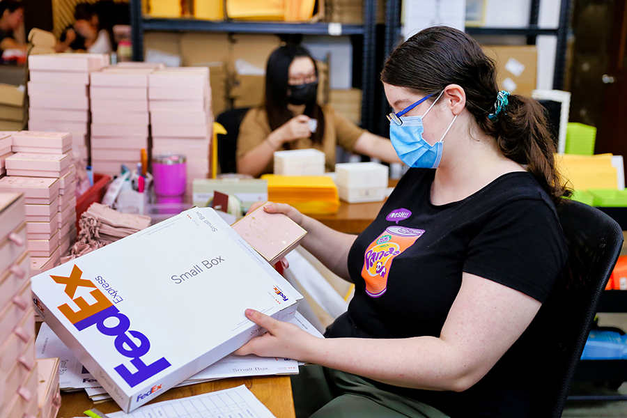 Female employee inserts jewelry product into FedEx packaging