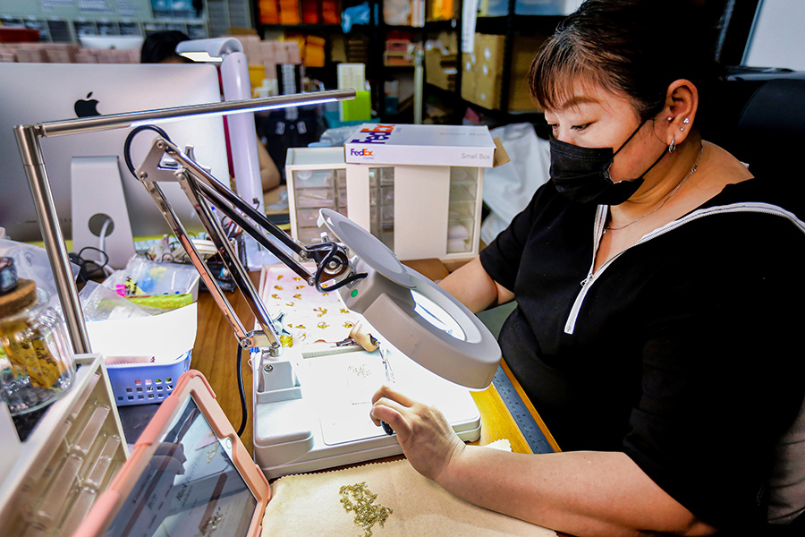 Female jewelry maker works at a desk