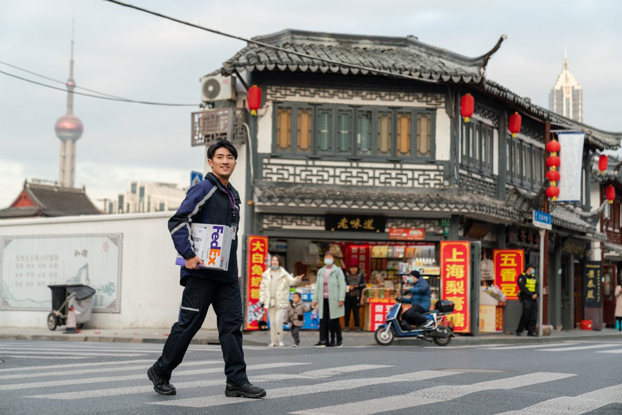 Male Chinese courier delivering parcel crosses street in China