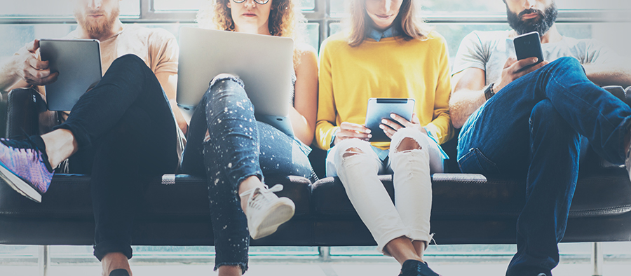 Group of young people sitting and using tablets and laptops