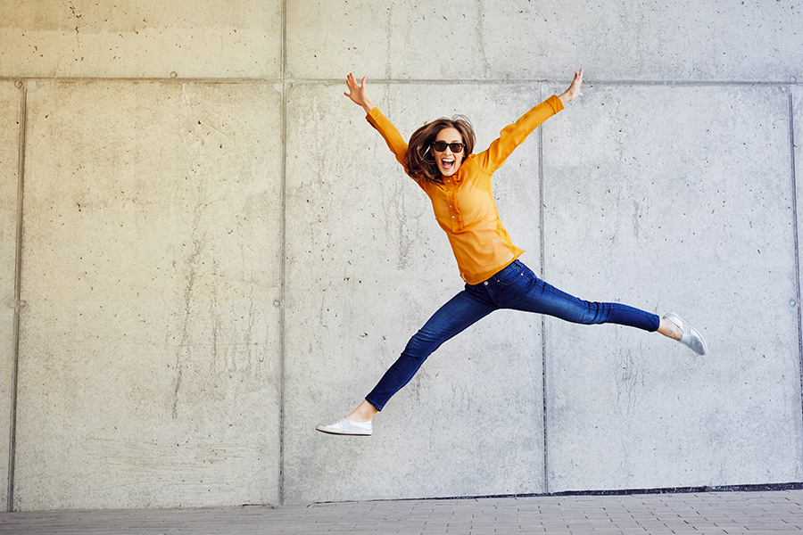 Girl jumping with happy face against wall
