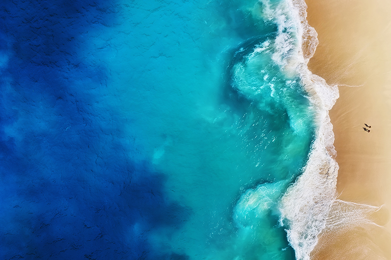 Overhead view of turquoise ocean and sandy shore