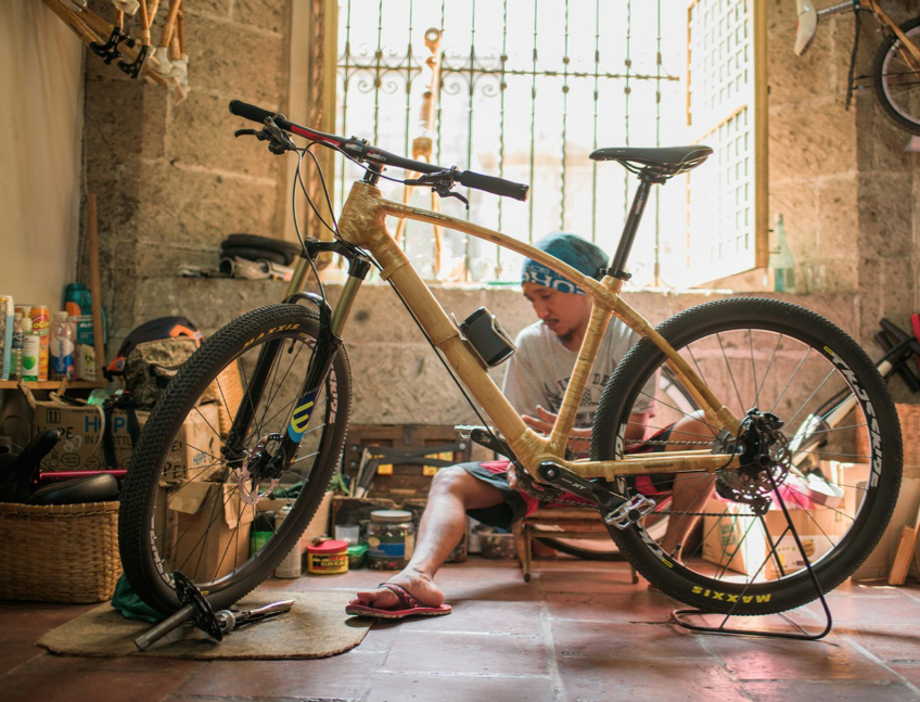 Filipino man sits inside a repair studio with a bike