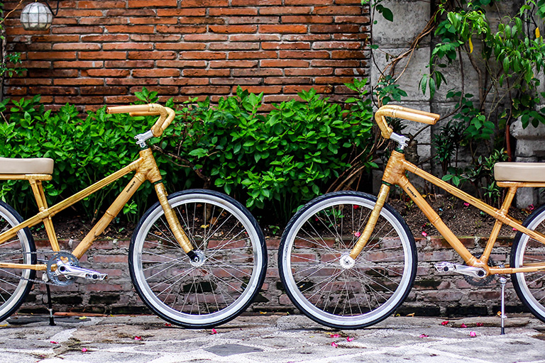 2 yellow bikes made from bamboo face each other on a residential street