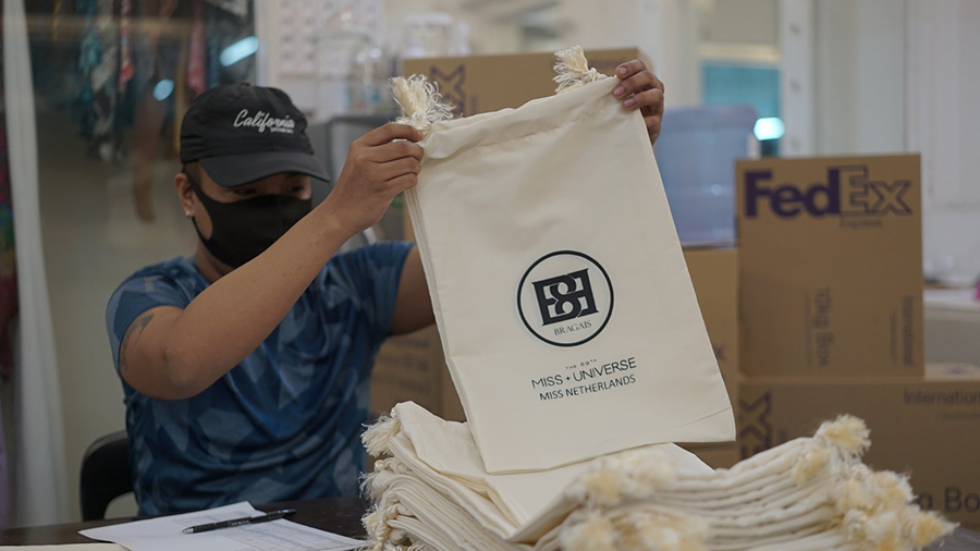 Worker packing Miss Universe cloth bag into FedEx boxes