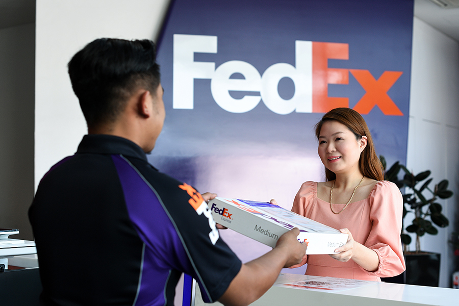 Asian female hands FedEx package over to male courier