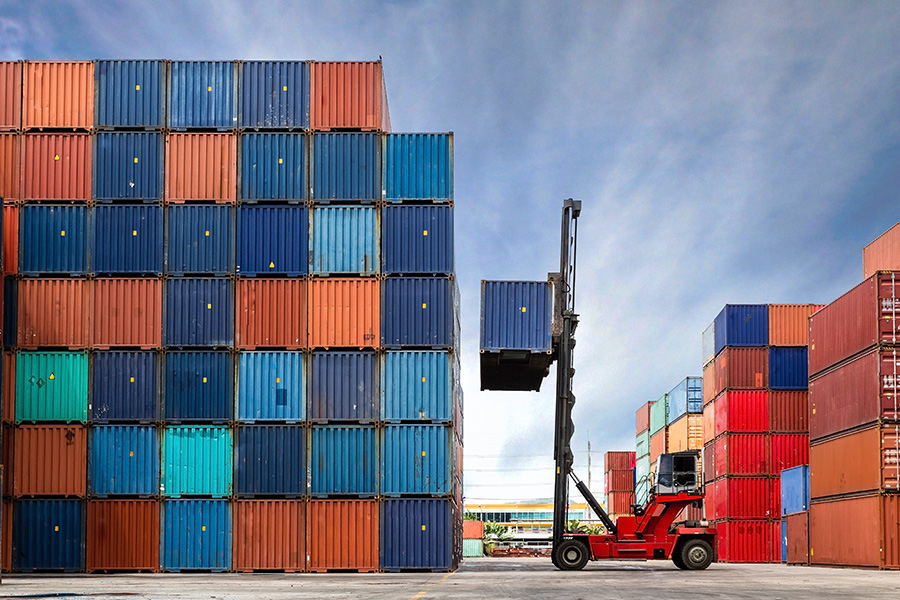 Forklift truck lifts container in shipping container yard