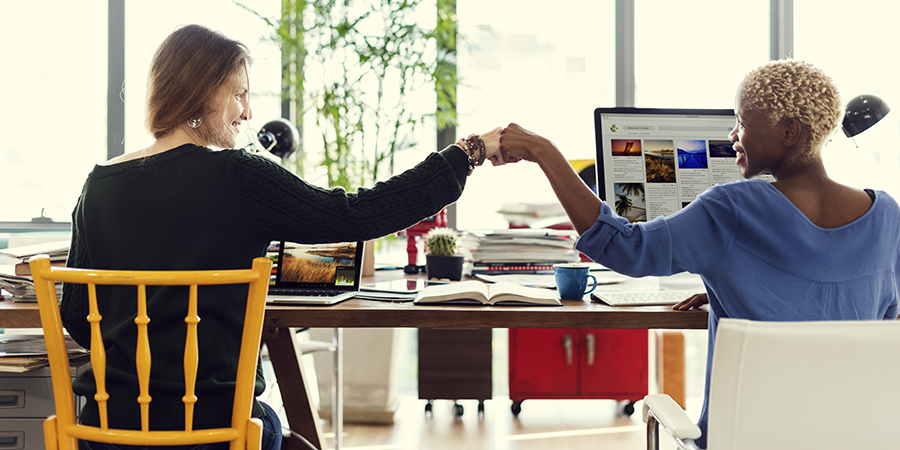 2 women at co-working space do fist-bump