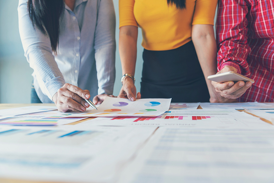 3 women collaborating at work over data and charts