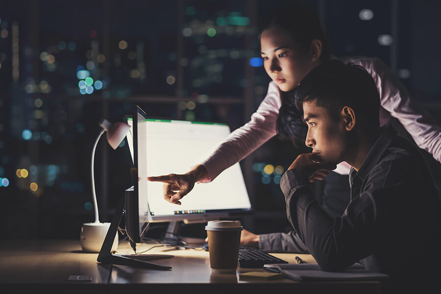 Male and female colleague discuss content on computer screen