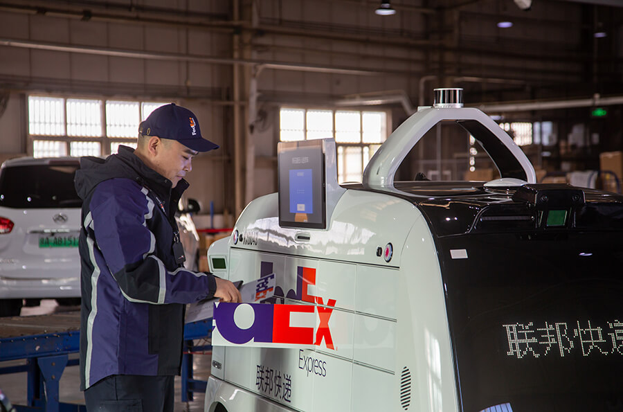 Chinese delivery driver in FedEx uniform with electric delivery device