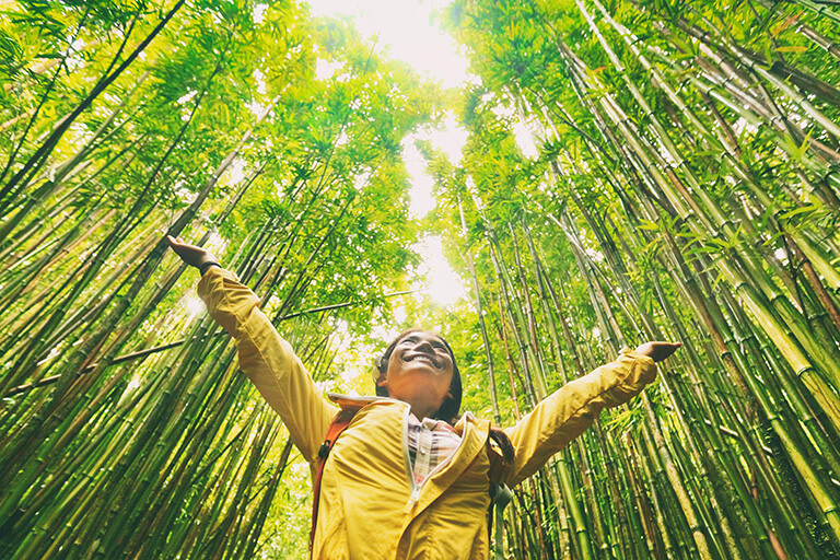 Woman standing with arms raised in a bamboo forest