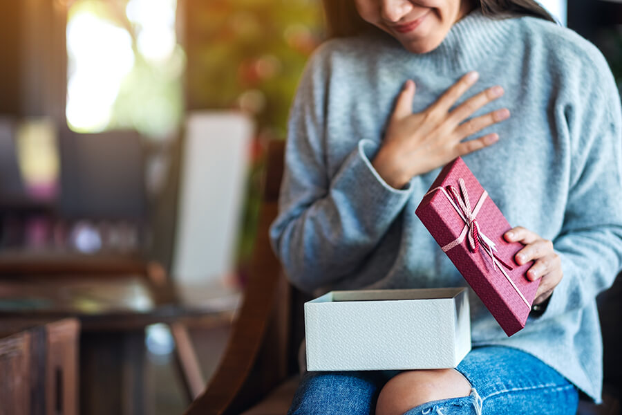 Smiling dark haired female in jeans opening present smiling