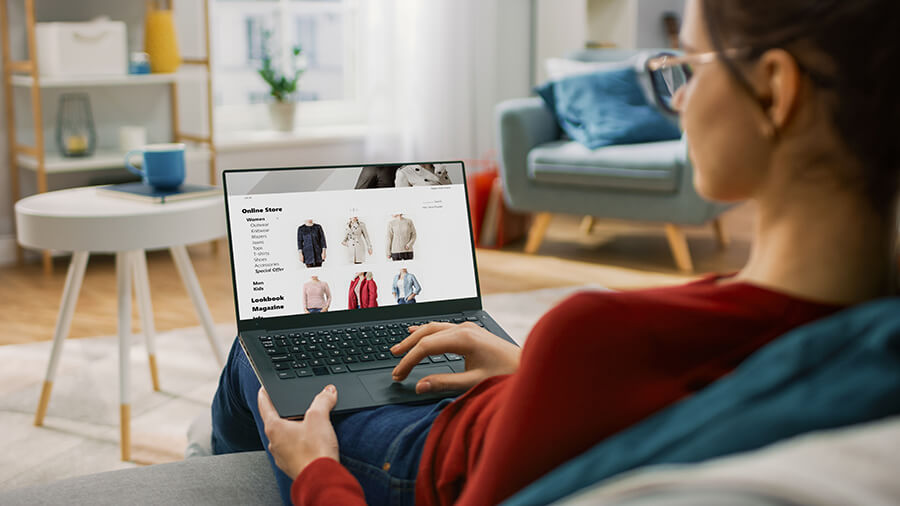 Female with glasses in red top browsing clothes on laptop screen