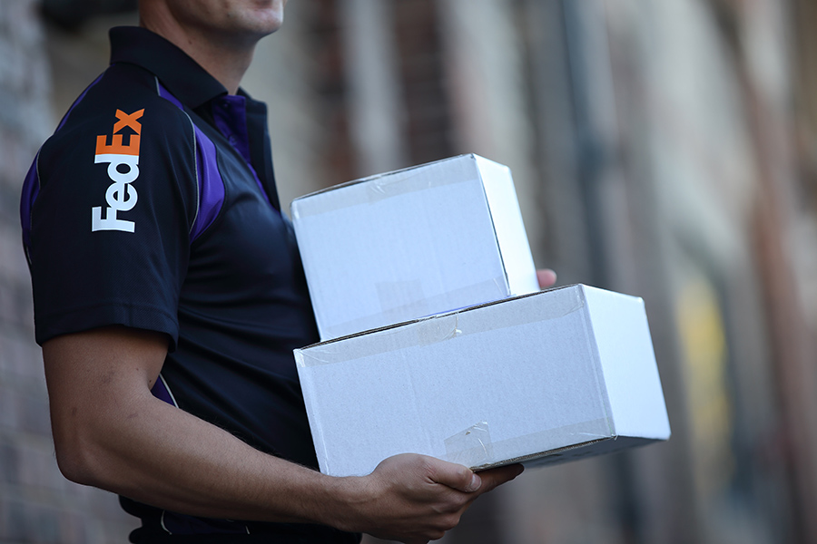 Male FedEx courier carrying 2 white boxes