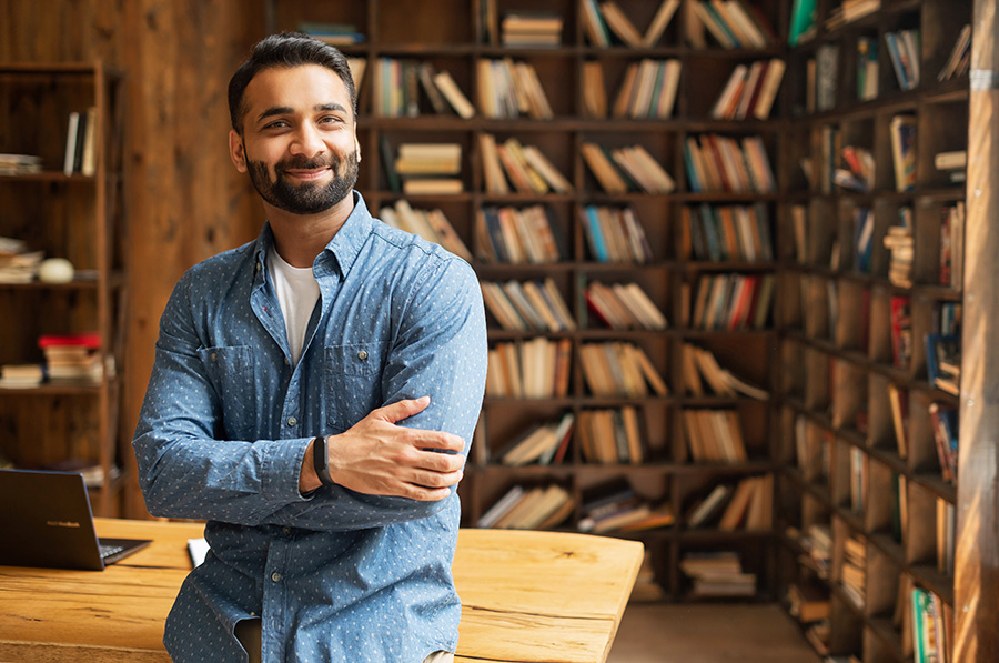 Smiling Indian male in blue shirt in bookstore