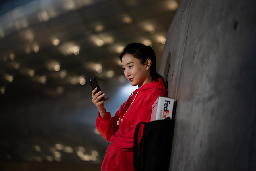 Chinese female with FedEx parcel in handbag on mobile phone at night