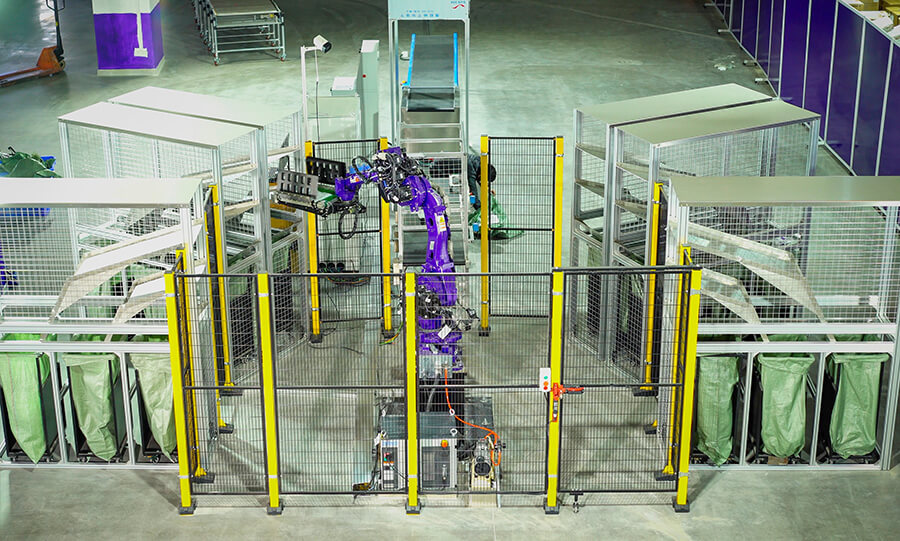 Purple robotic arm robot surrounded by sorting cages in warehouse