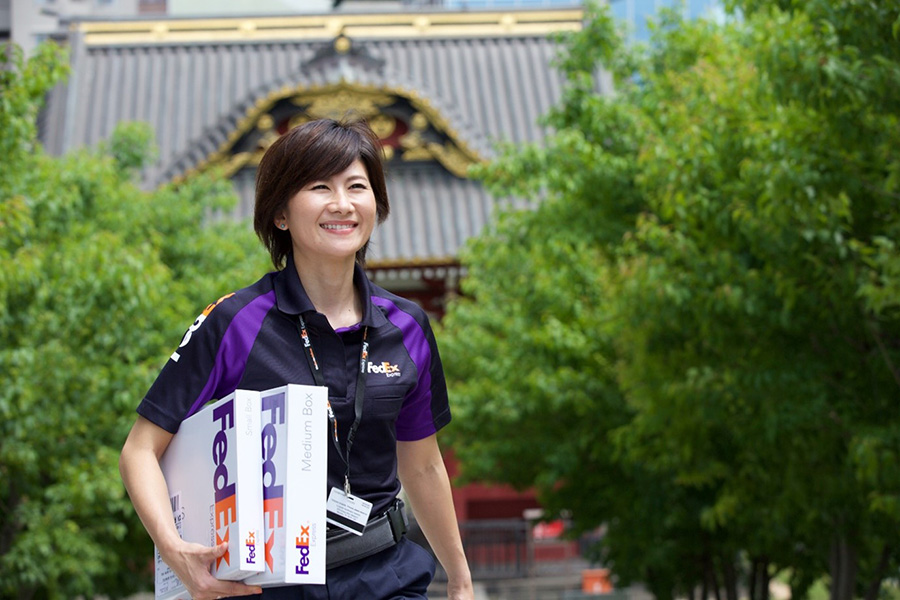 Smiling female FedEx employees carries packages