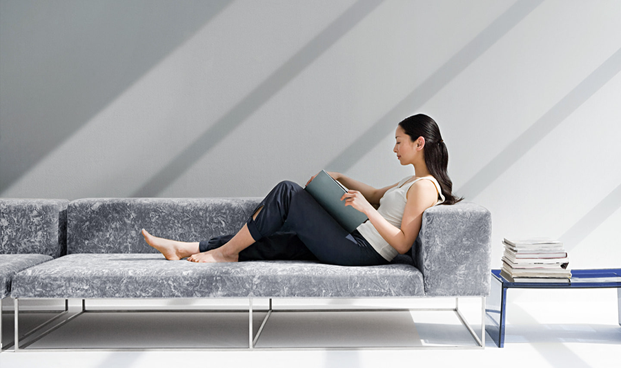 Korean woman sits on a gray couch