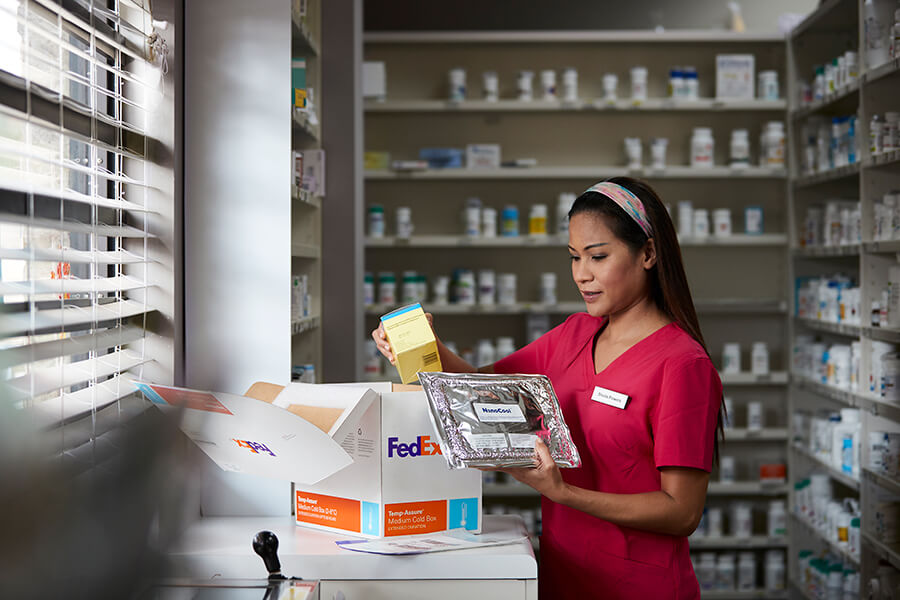 Pharmacy technician picking up temperature-controlled medical supplies from shipping box