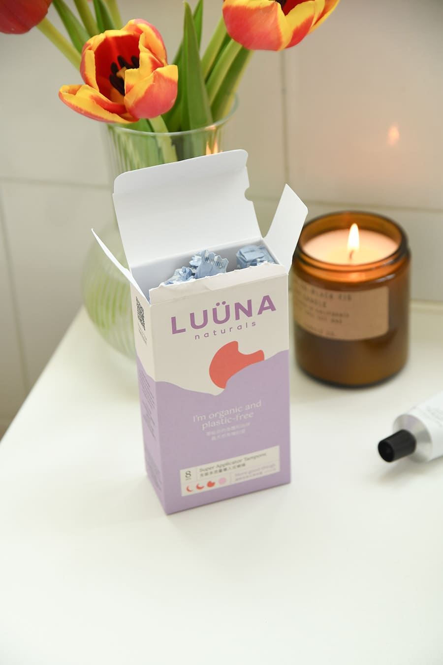 Open box of period products next to candle and flowers