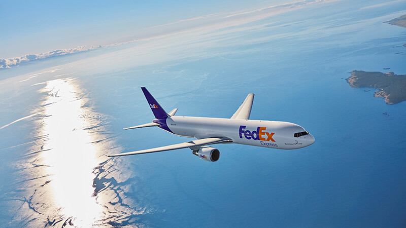 FedEx plane flying over the ocean