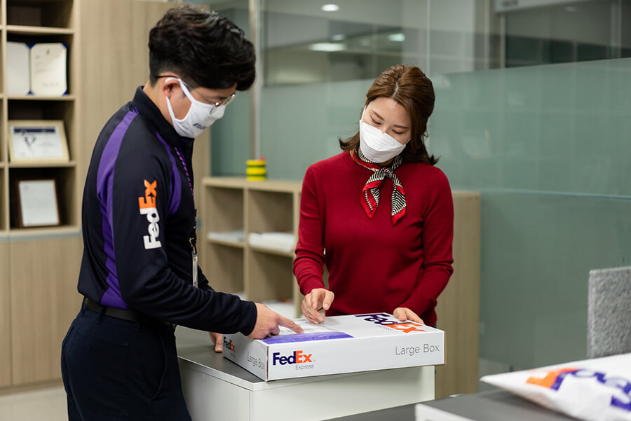 FedEx courier and customer with FedEx boxes and paperwork