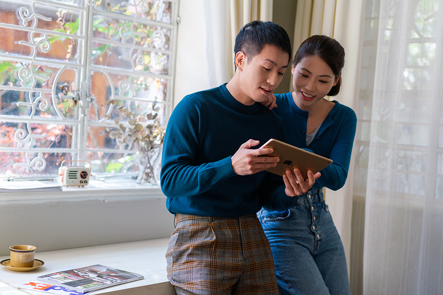 Asian couple holding tablet device and browsing