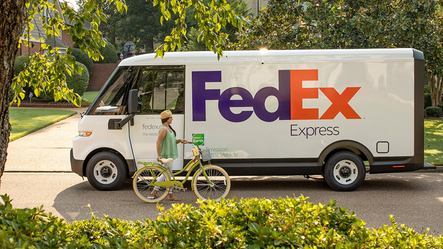 A woman pushing a bike along with FedEx electric vehicle