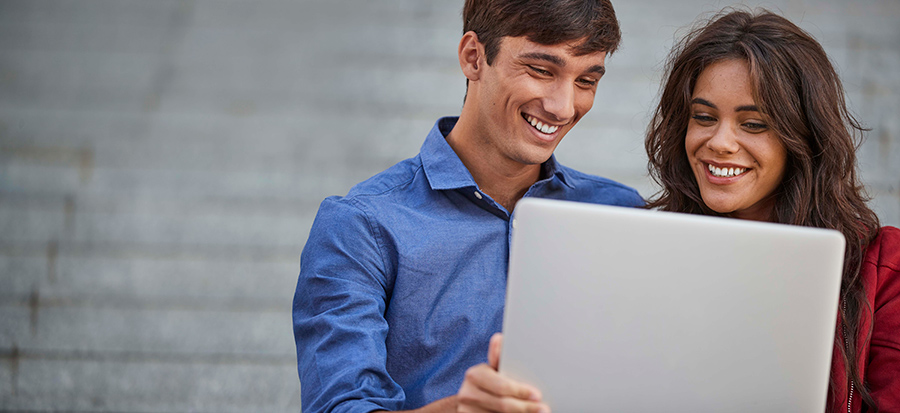 A man and a woman looking on a laptop’s screen with a smile