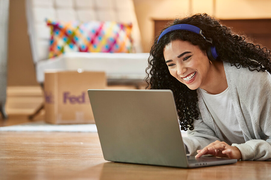 Young female with long curly hair and headphones laughing on laptop