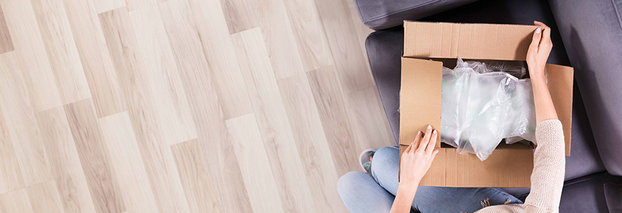 Female opening a cardboard delivery box at home on sofa