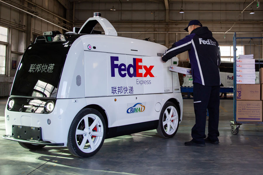 Chinese-male-courier-places-FedEx-packages-into-smart-delivery-vehicle