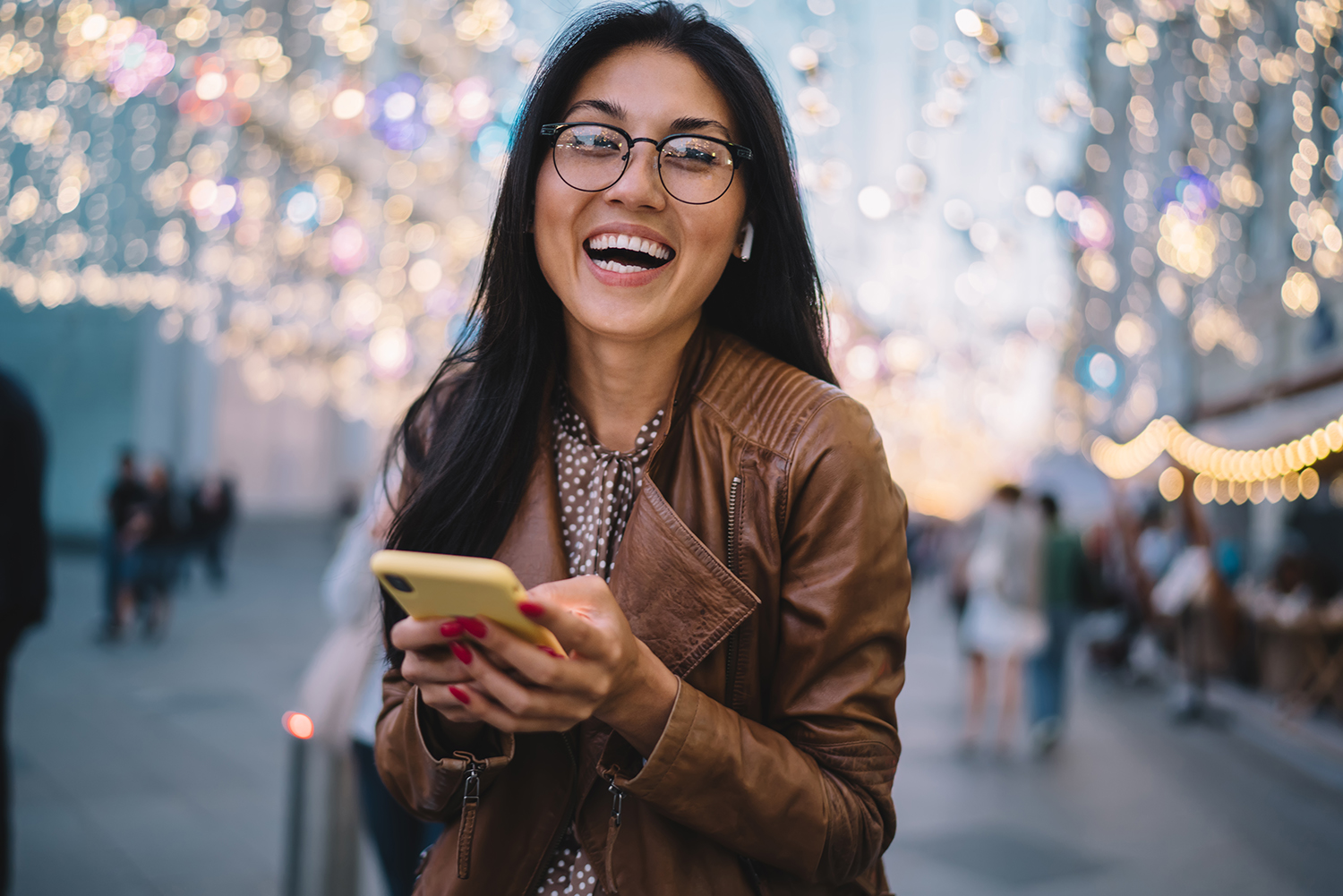 Laughing Asian female on street holding mobile phone