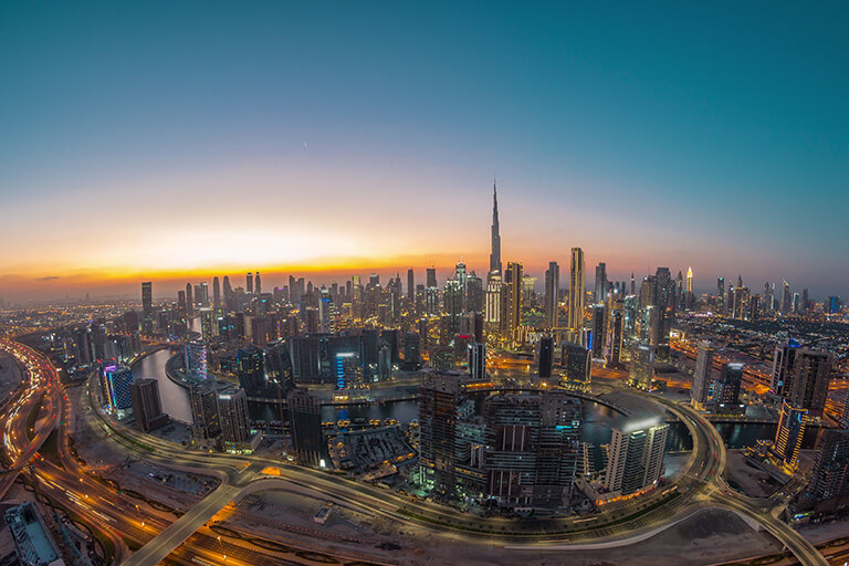 Illuminated Dubai skyline at sunset