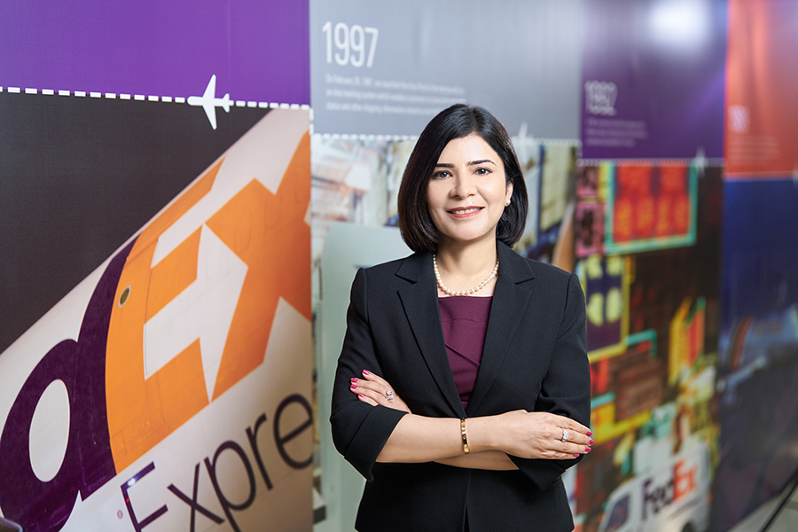 Indian female in black suit stands in front of corporate display board