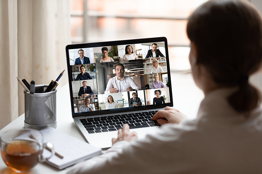 Female with dark hair facing laptop screen with conference call