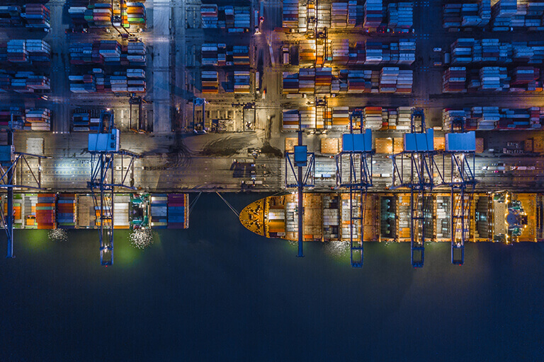 Two cargo ships being loaded at night