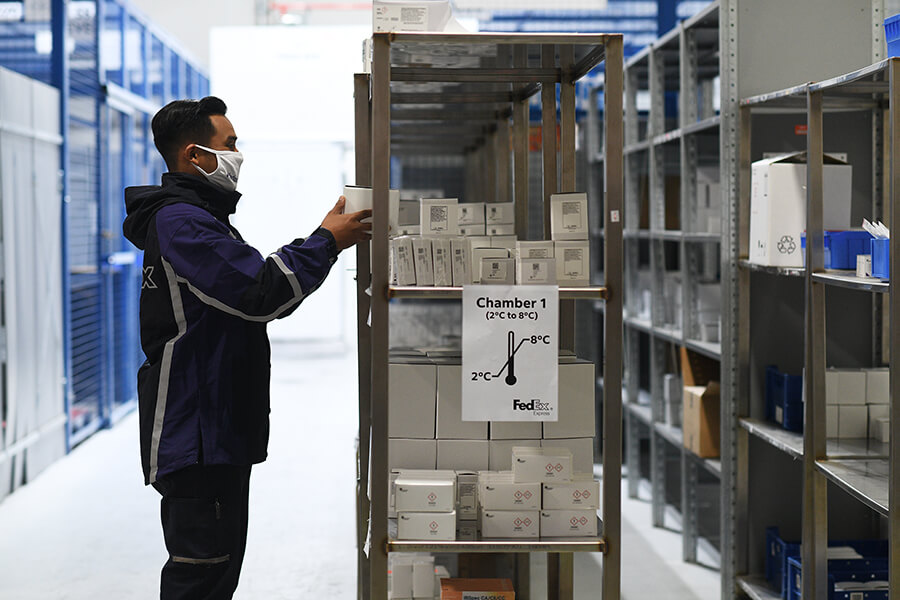 A FedEx courier putting vaccines on to the shelf