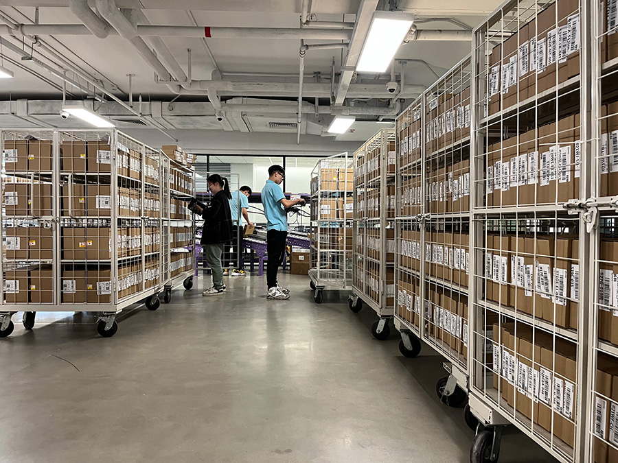 A warehouse full of parcels with 3 staff in the room